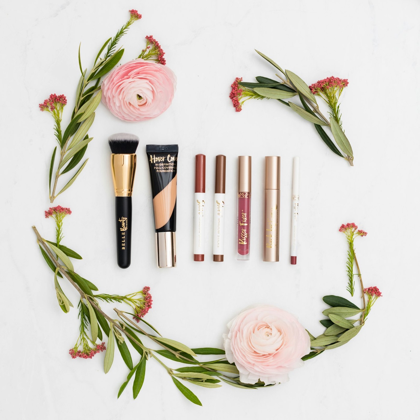 Beauty products and pink ranunculus on marble
